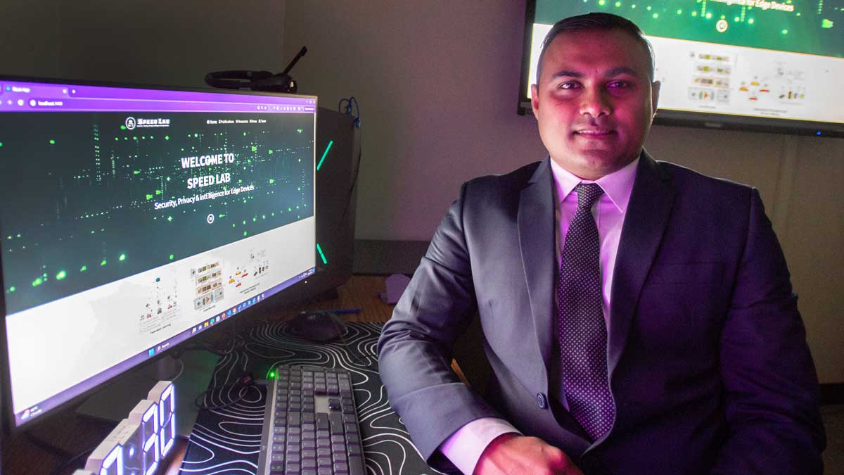 A professor sits next to his computer.