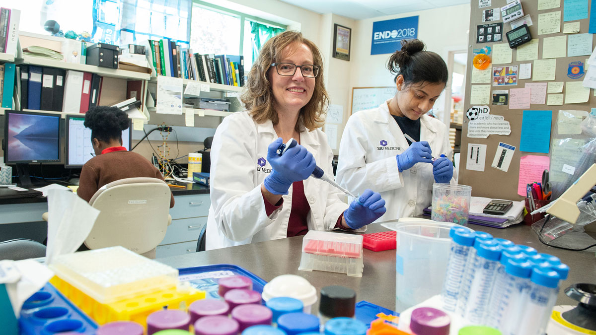 A professor and her students conduct research in a lab.