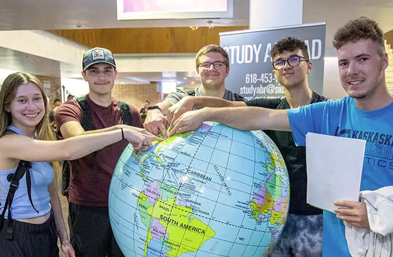 Students gathered around a large inflatable globe at a Study Abroad event at Southern Illinois University.